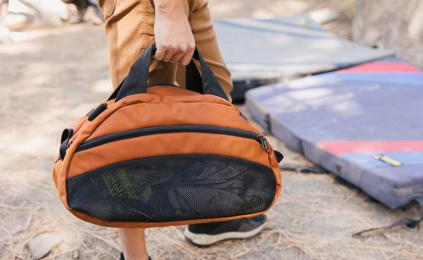 A person holding a filled Old School Carry All with items visible in the mesh compartment.